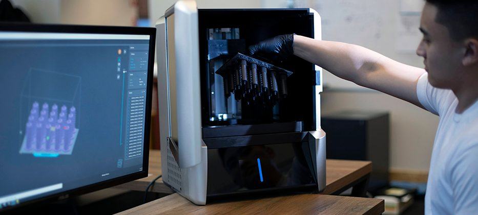 男子在电脑旁从XiP 3D打印机中取出一个零件